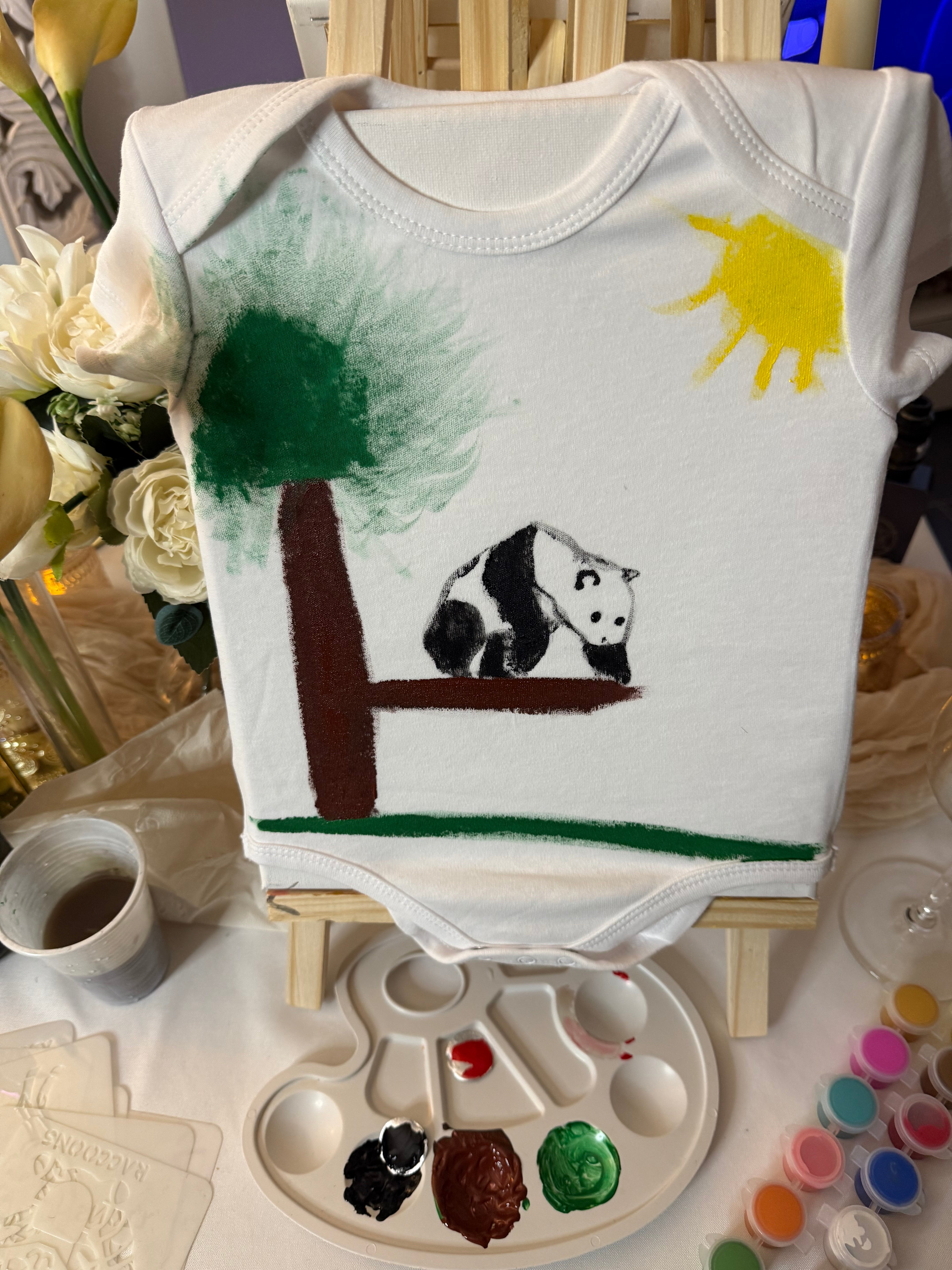 Body bébé blanc peint avec un arbre, un panda sur une branche, de l’herbe et un soleil jaune.